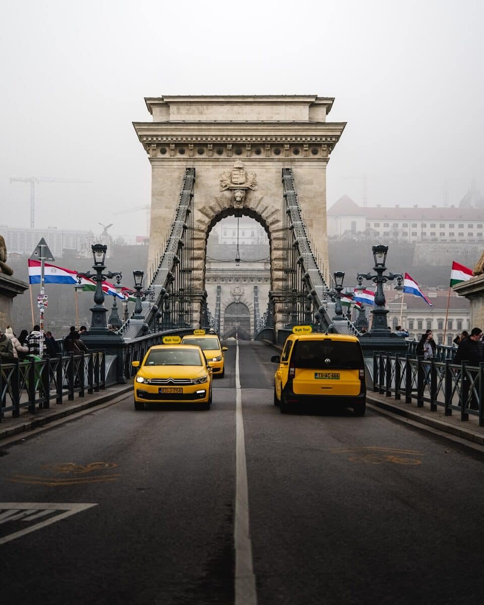 Yellow taxis crossing a bridge on a foggy day.