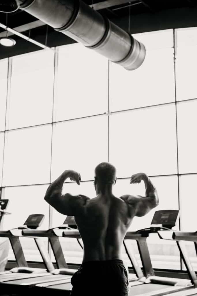 A bodybuilder flexes his muscles in a gym.