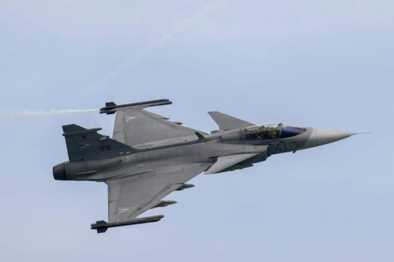 a fighter jet flying through a blue sky