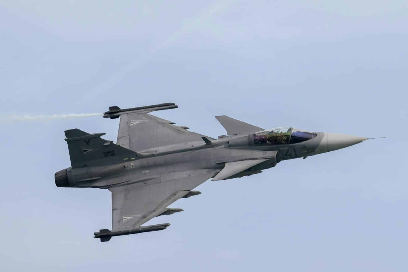a fighter jet flying through a blue sky