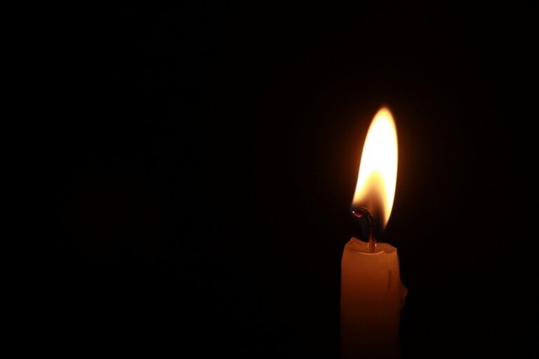 a lit candle in the dark with a black background