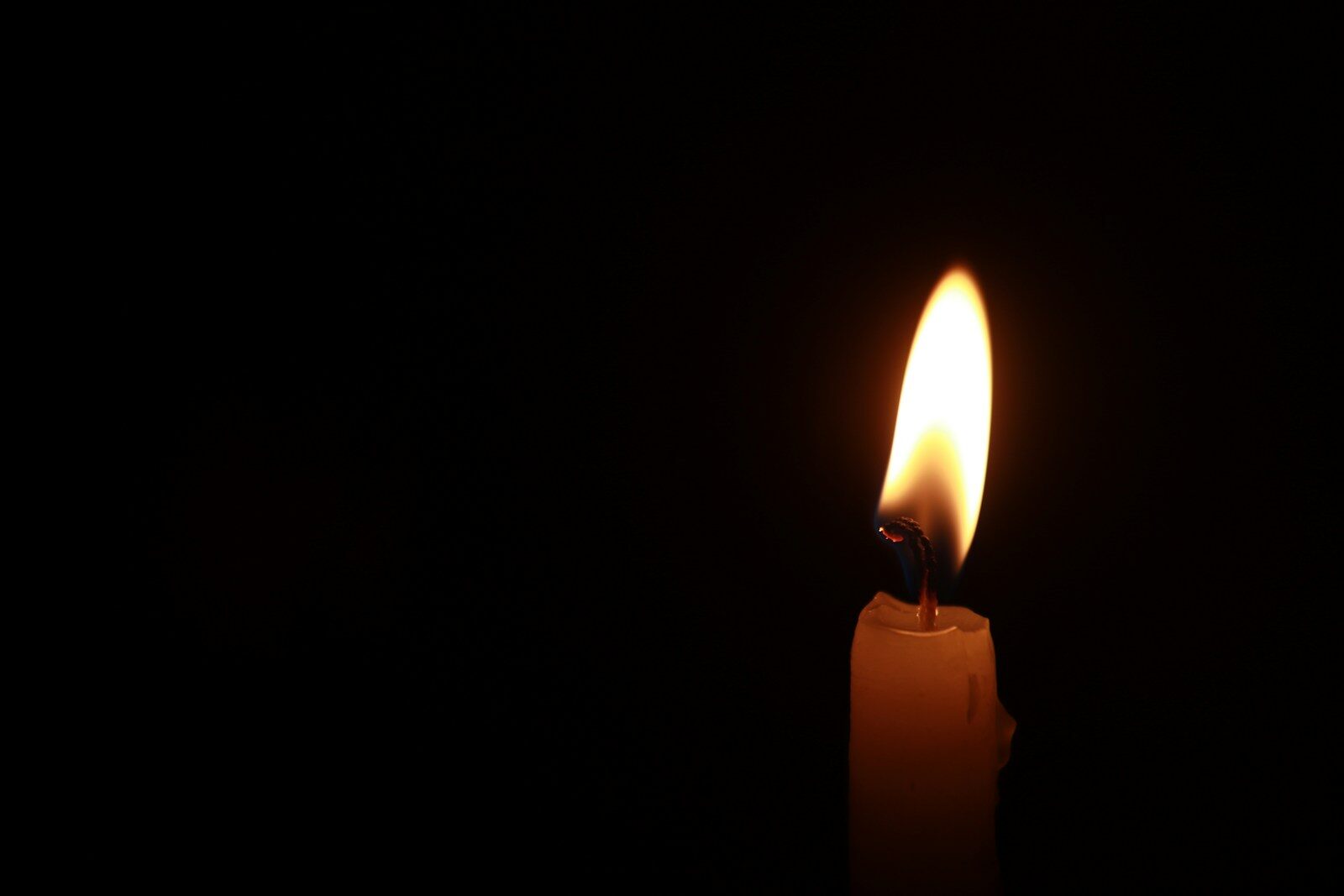 a lit candle in the dark with a black background