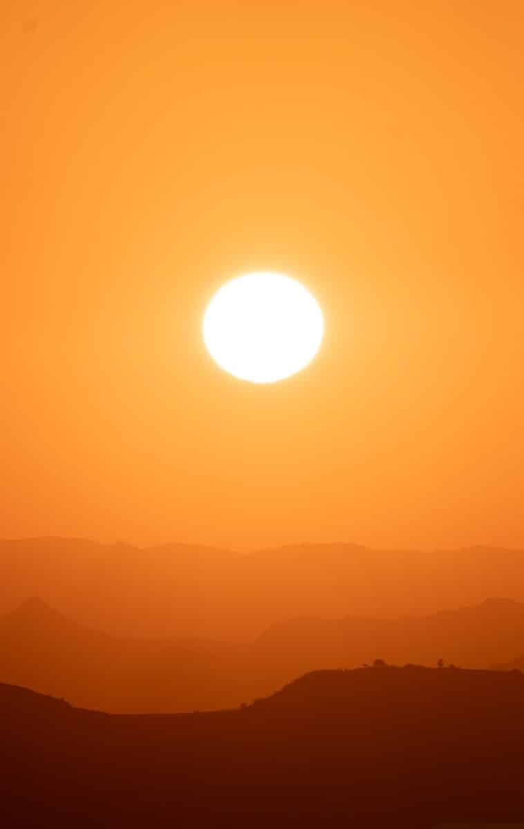 the sun is setting over a mountain range