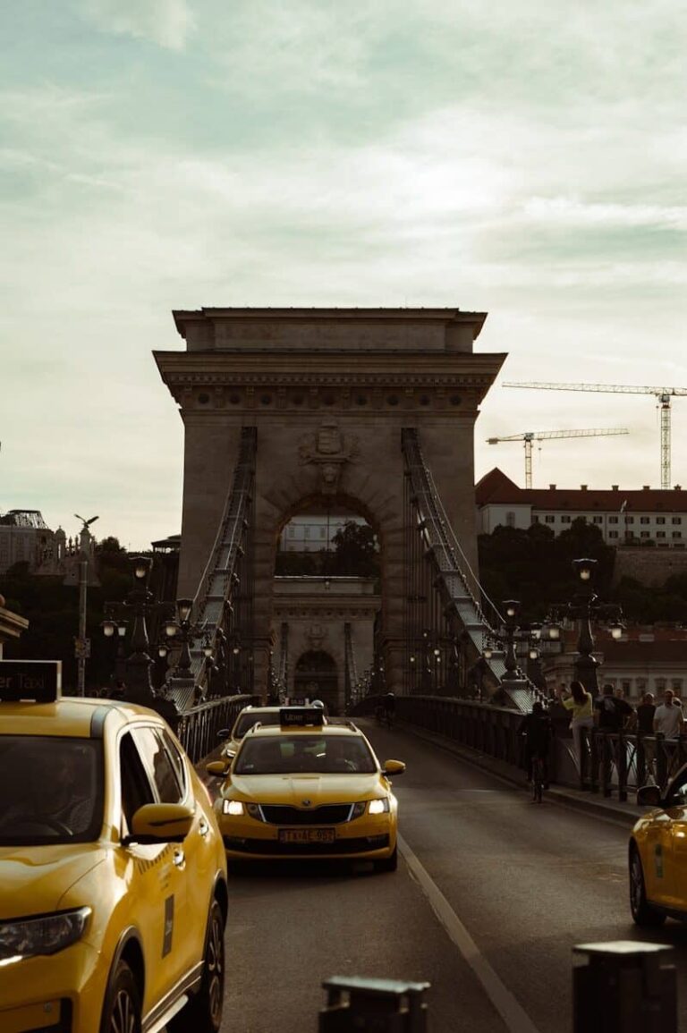 Yellow taxis on a bridge with a stone archway.